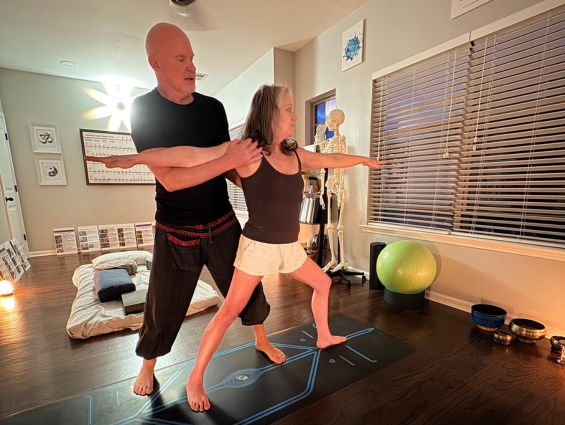 H2 A yogi being guided in their practice by an instructor. Only 2 people in shot